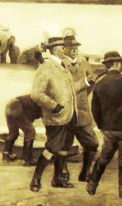 Több férfi áll egy folyónál, az egyik férfi öltönyben és kalapban beszélget a többiekkel.